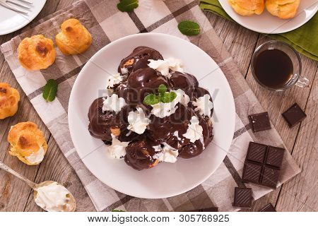 Chocolate Profiteroles With Whipped Cream On White Dish.