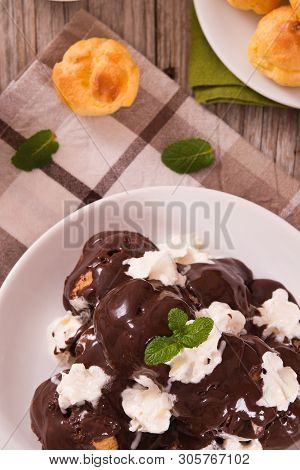 Chocolate Profiteroles With Whipped Cream On White Dish.