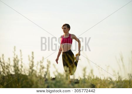 Young Woman Doing Stretching Outdoor. Warm up Exercise in the Hot Summer Evening. Sport and Healthy Active Lifesyle Concept.
