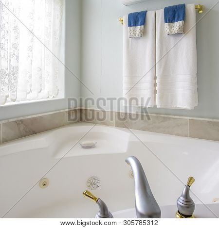 Square Frame Bathroom Interior With Agleaming Bathtub Beside A Large Arched Window