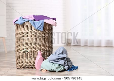 Wicker Laundry Basket With Dirty Clothes And Detergent On Floor Indoors. Space For Text