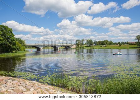 City Jelgava, Latvian Republic. River Lielupe,  People Are Driving Catamaran. Bridge And Water. Jun