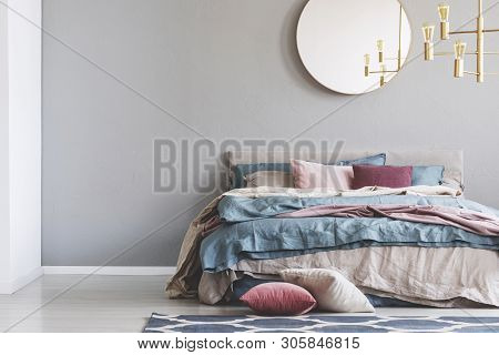 Chick Round Mirror On Grey Empty Copy Space Wall In Elegant Bedroom Interior With Warm Bed With Blue