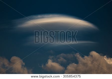 Rare Lenticular Cloud Altocumulus Lenticularis On Top Of A Cumulus Cloud In Front Of A Blue Sky