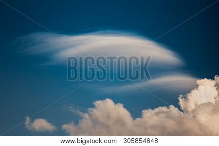 Rare Lenticular Cloud Altocumulus Lenticularis On Top Of A Cumulus Cloud In Front Of A Blue Sky