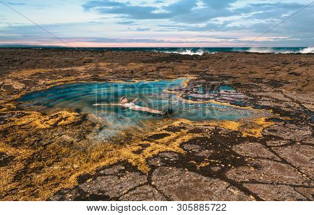 On Vacation A Female Floats On Her Back In A Rock Pool By The Ocean. The Rock Pools Are Flushed Clea