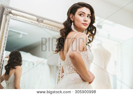 Beautifu bride choosing wedding dress in a wedding salon
