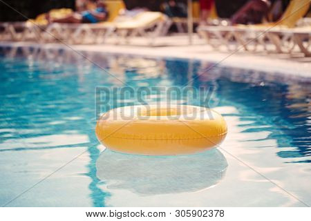 floating ring on blue water swimpool with waves reflecting in the summer sun
