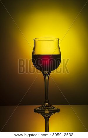A Glass Of Red Wine On The Table On A Yellow-orange Background.