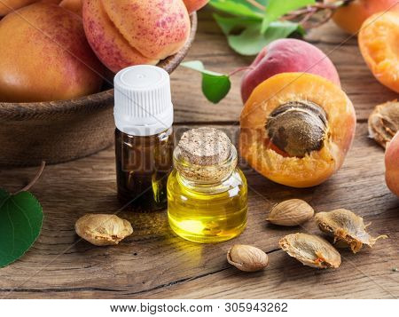 Apricot kernel oil and apricot kernels on wooden background.