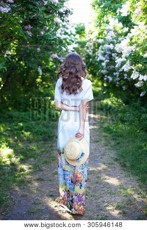 Girl In A Straw Hat With A Blue Ribbon On A Spring Afternoon. Back View. Trendy Casual Summer Or Spr