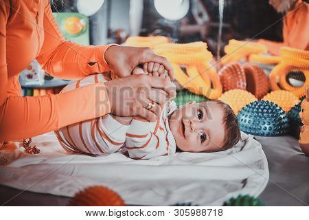 Happy Smiling Cute Toddler Is Lying On The Special Table Surrounded By Ortopedic Toys While Expirien