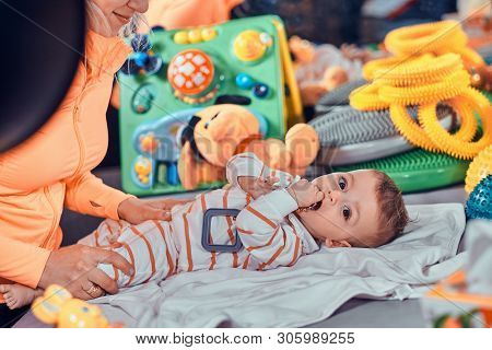 Happy Smiling Cute Toddler Is Lying On The Special Table Surrounded By Ortopedic Toys While Expirien