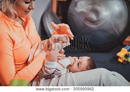 Joyful Happy Mom Is Playing With Her Newborn Baby While Waiting For A Doctor At Pedeatrician Cabinet