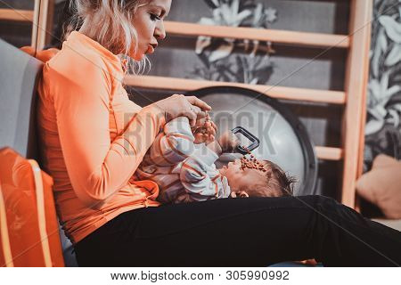 Joyful Happy Mom Is Playing With Her Newborn Baby While Waiting For A Doctor At Pedeatrician Cabinet