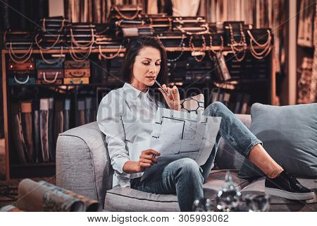Beautiful Young Designer Is Sitting On The Sofa At Her Curtians Atelier While Watching Drawings Abou