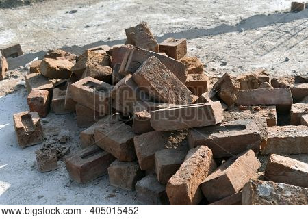 A Large Brick On A Poor Unsworned Rural Road Littered With Broken Brick Fragments, Stones, Construct