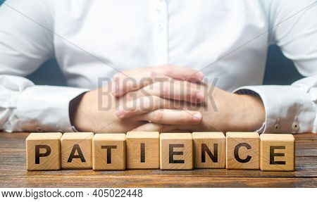 Man Folded His Hands On A Background Of Blocks With The Word Patience. Patience In Anticipation, Per