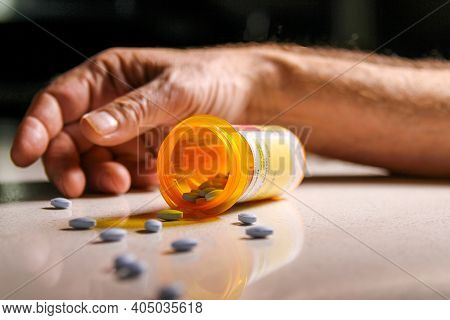 Prescription Medication Spilling On To The Floor With An Addicts Hand In Background. Depicting Curre