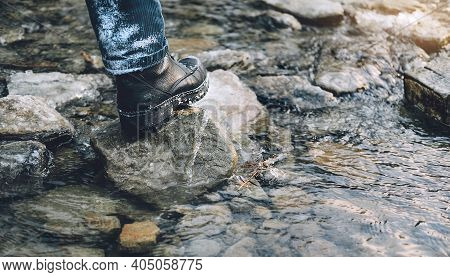 Hiking Shoes On Hiker Outdoors Walking Crossing Mountain Creek. Man On Hike Trekking In Nature. Clos