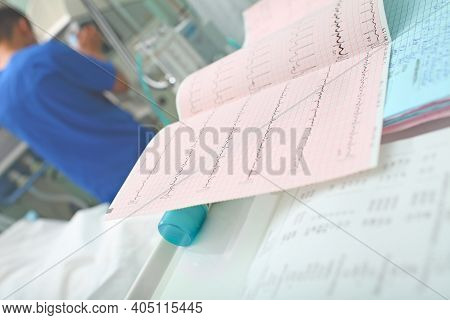 Ecg Tracing And Other Test Results At The Nursing Station On The Background Of Working Male Doctor I