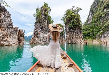 Back View Of Young Female Tourist In Dress And Hat At Longtail Boat Near Three Rocks With Limestone 