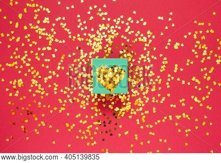 Gift Box Covered With Gold Sparkles In The Shape Of A Heart On Red Background With Place For Text Ha