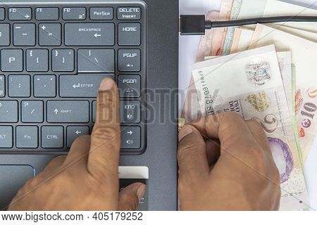 Top View Hand Put On Baknote And Black Keyboard On Notebook Have And A Memory Card Plugged Into Comp
