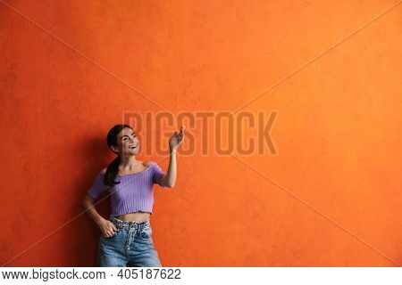 Portrait of cheerful young woman prsenting copy space while standing over isolated background