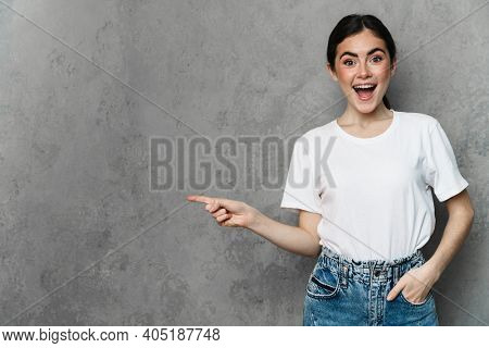 Portrait of cheerful young woman prsenting copy space while standing over isolated background