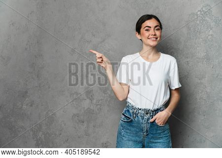 Portrait of cheerful young woman prsenting copy space while standing over isolated background