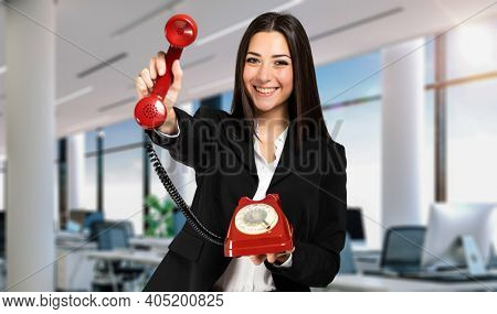 Young female manager holding a red vintage phone, contacs us concept