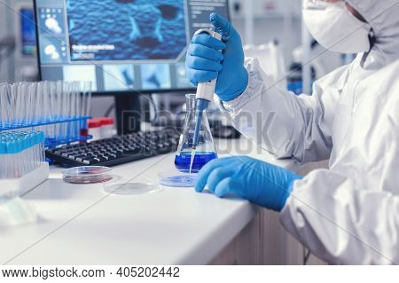 Microbiologist In Coverall Pouring Sample On Petri Dish With Micropipette . Chemist In Modern Labora