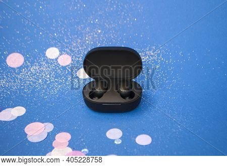 Ear Buds On Bright Classic Blue Background With Colorful Confeti And Sparklets. Festive Background.