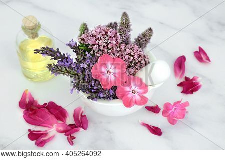Natural herbal medicine with  flowers and herbs in a mortar and  pestle with oil bottle and rose petals on marble. Still life for naturopathic health care for aromatherapy essential oil preparation.