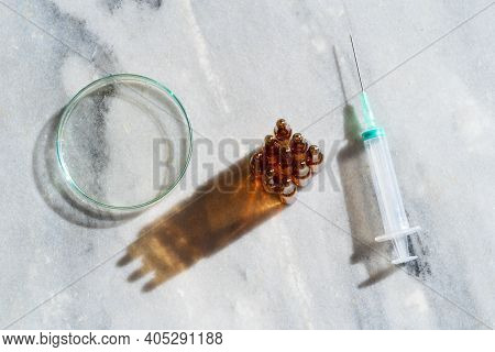 Glass Petri Dish With Transparent Pure Serum For Skin Care With Ampulas Ans Syringe On Marble White 