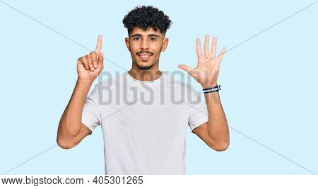 Young arab man wearing casual white t shirt showing and pointing up with fingers number six while smiling confident and happy. 