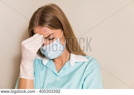 Tired Nurse With With Protective Mask And Gloves Having Headache.