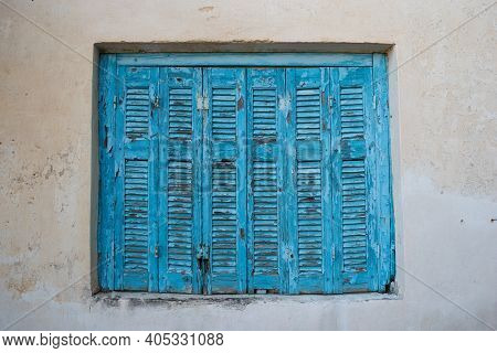 Old Wooden Window Blue Shutters Of A House's Wall Facade In Greece.
