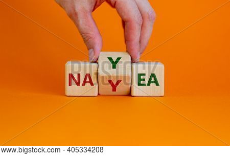 Yea Or Nay Symbol. Businessman Turns A Cube, Changes The Word 'nay' To 'yea'. Beautiful Orange Backg