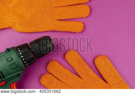 Handheld Power Tools, Repair Services, Or Home Handyman. Electric Drill And Redwork Gloves On A Purp