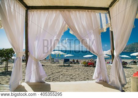 Alanya, Turkey -October 20, 2020: Luxury wood framed whit  curtains for relaxing on the sandy beach in Alanya,  Turkey.