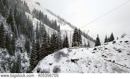 A Broken Gazebo Stands On A Snowy Hill In The Mountains. A Beautiful Gorge With Tall Fir Trees And S