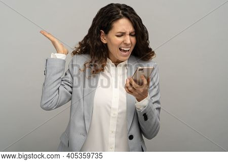 Studio Portrait Of Angry Business Woman Screaming Loudly Into A Mobile Phone, Shouting Calling On Sm