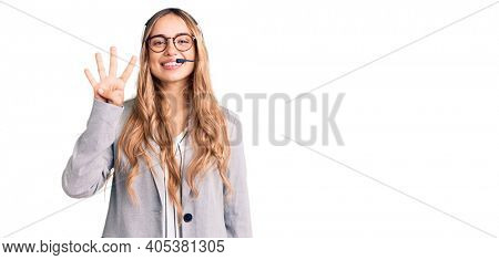 Young beautiful blonde woman wearing call center agent headset showing and pointing up with fingers number four while smiling confident and happy. 