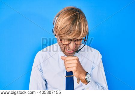 Young blond man wearing call center agent headset feeling unwell and coughing as symptom for cold or bronchitis. health care concept. 