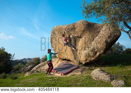 Two Young Girls Climb Bouldering Outdoors. Rock Climber Climbs A Difficult Route. Do Sports Outside 