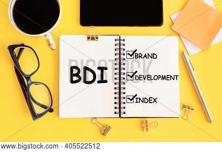 Bdi - Brand Development Index. Text On Notepad And Office Accessories On Yellow Desk.