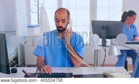 Medical Receptionists Working In Hospital Clinic Answering At Phone, Writing On Computer, Making App