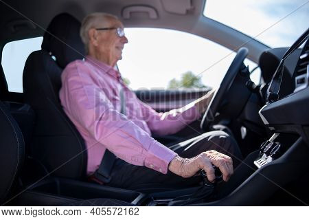 Interior Shot Of Smiling Senior Man Enjoying Driving Car With Hand On Gear Shift